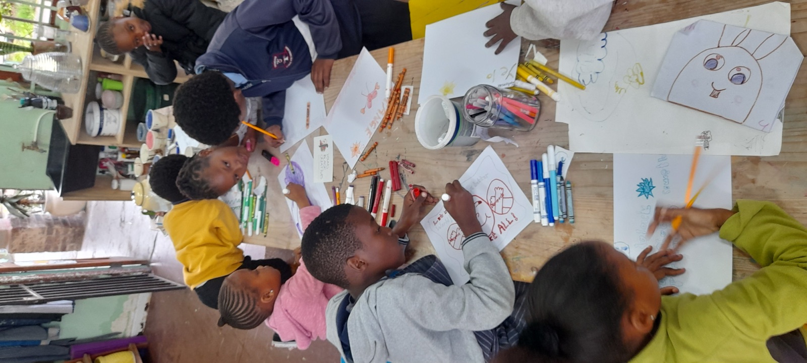 Children draw and color together around a studio table