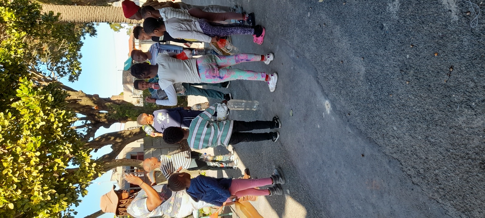 Children gather outdoors with an adult for a group activity